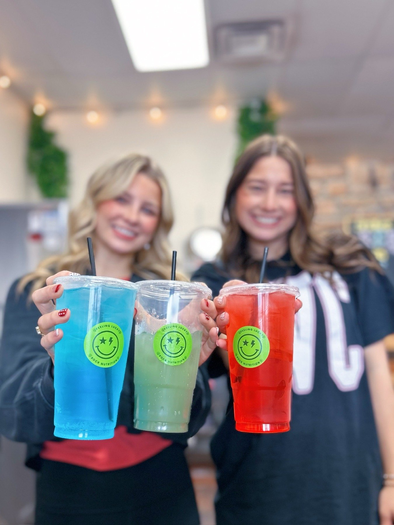 Two friends holding up bright Rock Nutrition energy teas together