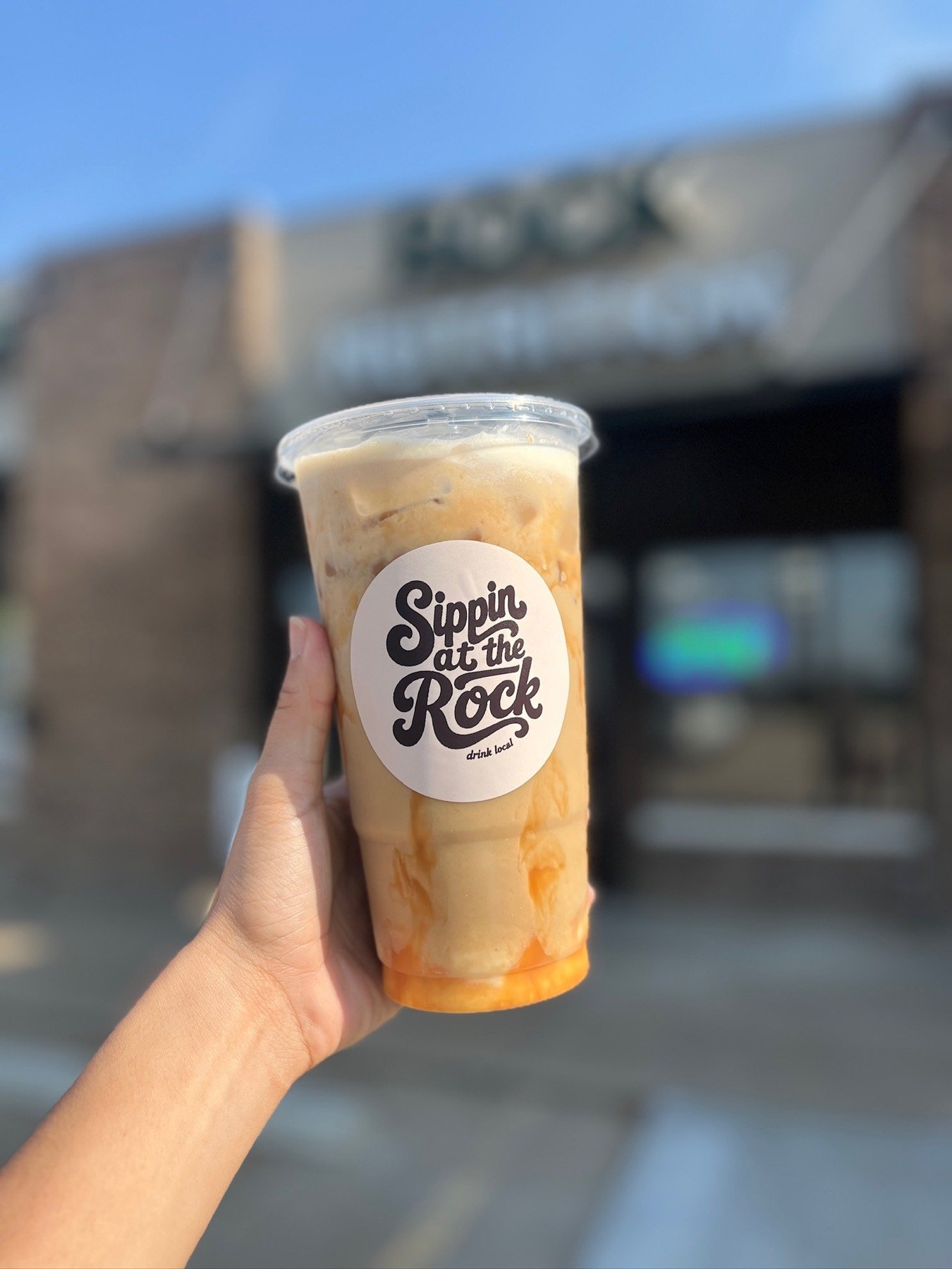 A Sippin at the Rock cup held up outside the Owasso shop